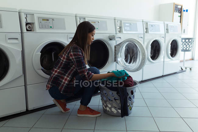 Young woman with basket full of clothes in wash house — Stock Photo