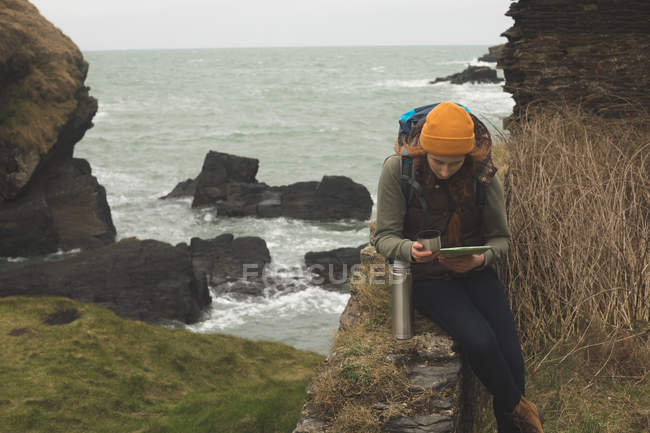 Konzentrierte Wanderin liest Landkarte und trinkt — Stockfoto
