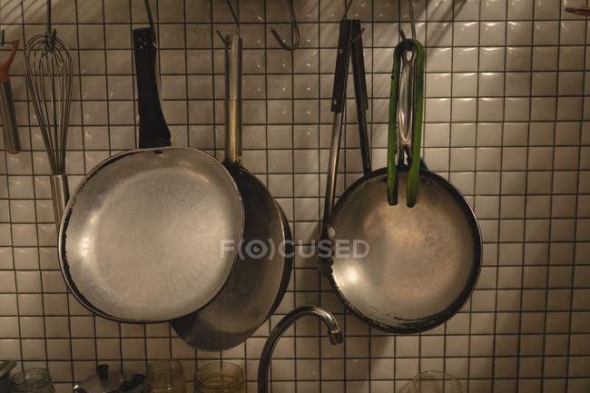 Varios sartenes de cocina colgados en una pared en la cafetería - foto de stock