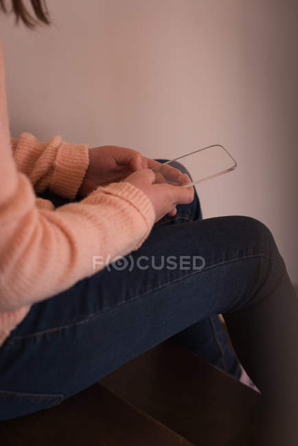 Partie médiane de la fille en utilisant un téléphone portable en verre à la maison — Photo de stock