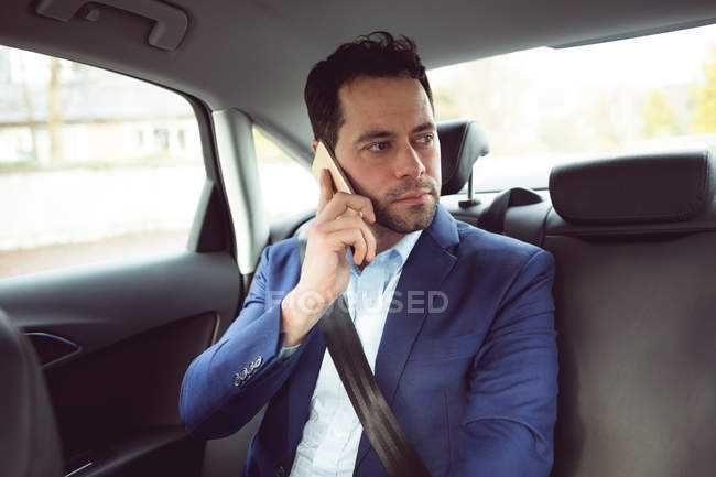 Бизнесмен разговаривает по мобильному телефону в современной машине — стоковое фото