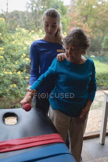 Physiotherapist assisting a senior woman with physiotherapy exercises — Stock Photo