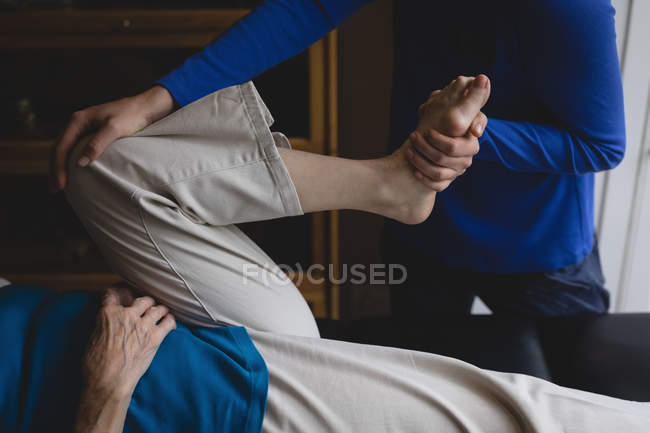 Physiotherapist assisting a senior woman with physiotherapy exercises at home — Stock Photo