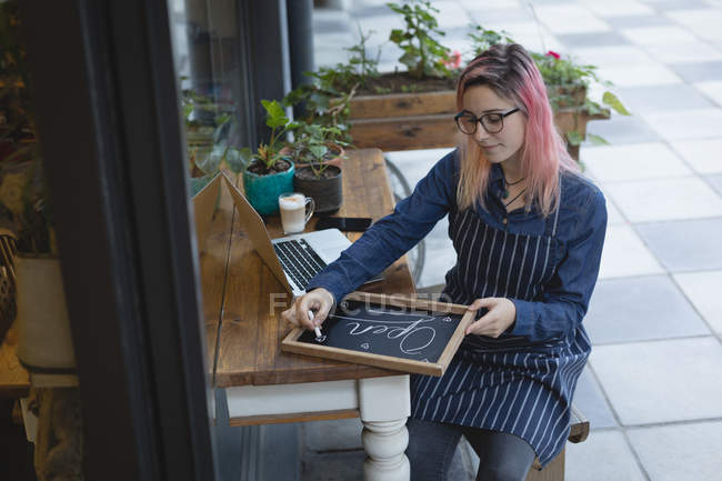 Barista writing on slate with a chalk at the coffee shop — Stock Photo