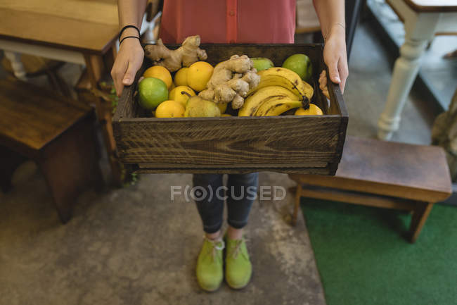 Низька частина молодої жінки тримає в руці лоток овоча — стокове фото