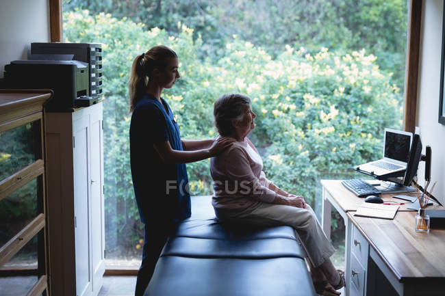 Fisioterapista che fa un massaggio alla donna anziana a casa — Foto stock