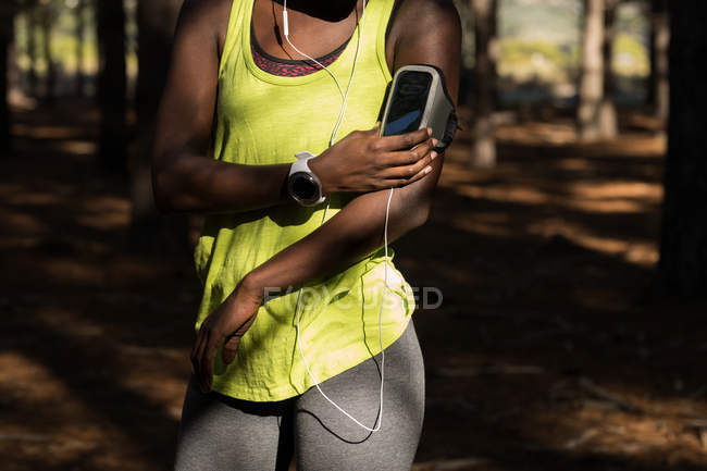 Partie médiane de l'athlète féminine à l'écoute de la musique du lecteur mp3 smartphone — Photo de stock