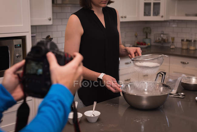 Pessoa fotografar mulher enquanto cozinha comida na cozinha em casa — Fotografia de Stock