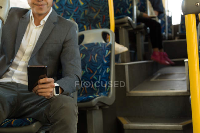 Средняя часть человека с помощью мобильного во время путешествия в автобусе — стоковое фото
