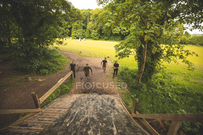 Grupo de homens treinando sobre curso de obstáculos no campo de treinamento — Fotografia de Stock