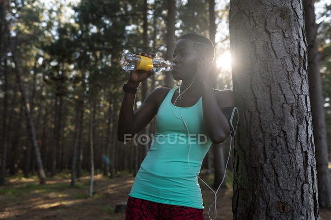 Atleta feminina bebendo água na floresta — Fotografia de Stock