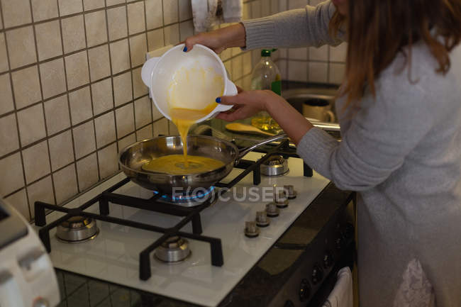 Woman preparing omelette in kitchen at home — Stock Photo