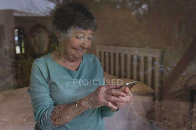 Seniorin benutzt Handy zu Hause — Stockfoto