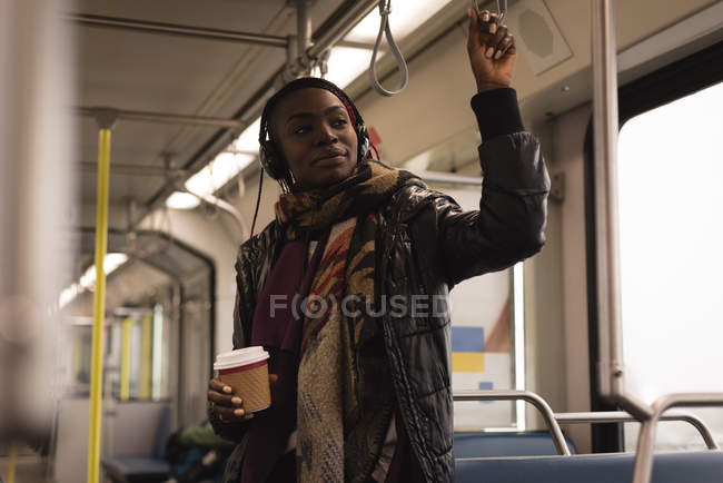 Mulher ouvindo música em fones de ouvido enquanto viaja no trem — Fotografia de Stock