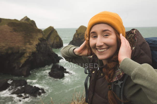 Beautiful smiling female hiker standing near sea coast — Stock Photo