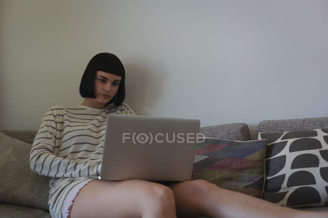 Woman using laptop in living room at home — Stock Photo