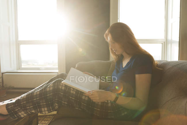 Donna che legge un libro in salotto a casa — Foto stock