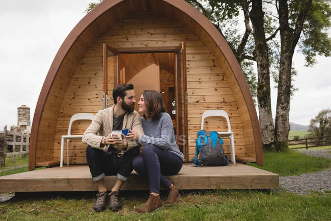 Couple affectueux prenant un café à l'extérieur de la cabane en rondins — Photo de stock