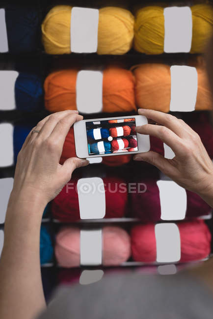 Close-up woman taking photo of yarn with mobile phone in tailor shop — Stock Photo
