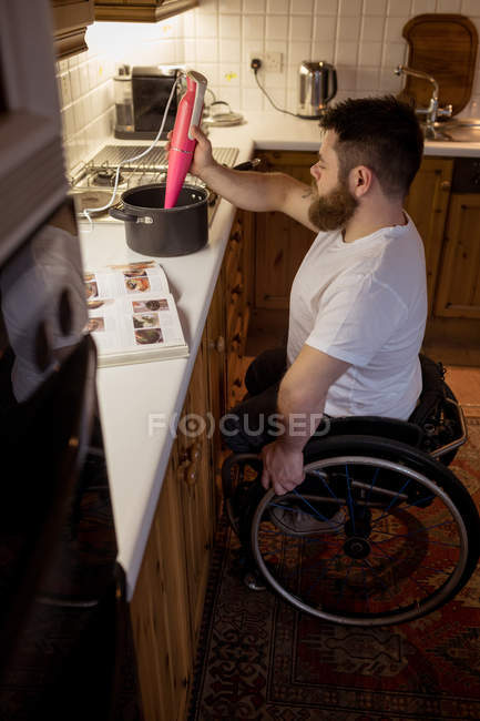 Homem com deficiência reparando uma panela na cozinha em casa — Fotografia de Stock