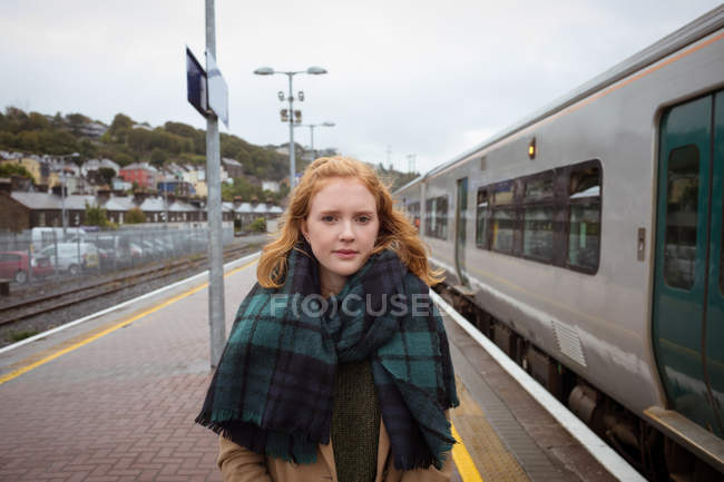 Portrait of young woman standing on platform besides train — Stock Photo