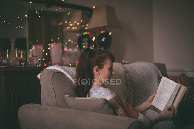 Frau liest zu Hause im Wohnzimmer ein Buch — Stockfoto