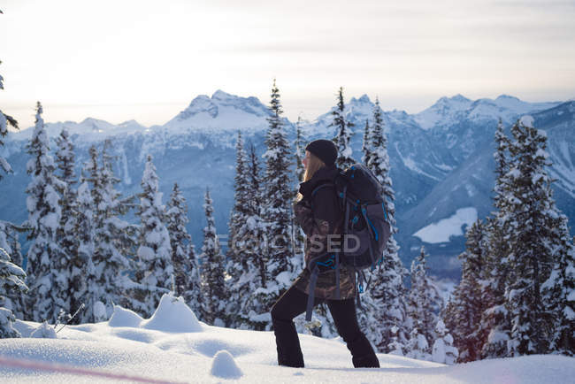 Seitenansicht einer Frau, die auf einer verschneiten Landschaft wandelt — Stockfoto