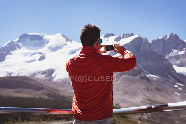 Чоловік фотографує мобільний телефон у сонячний день — стокове фото