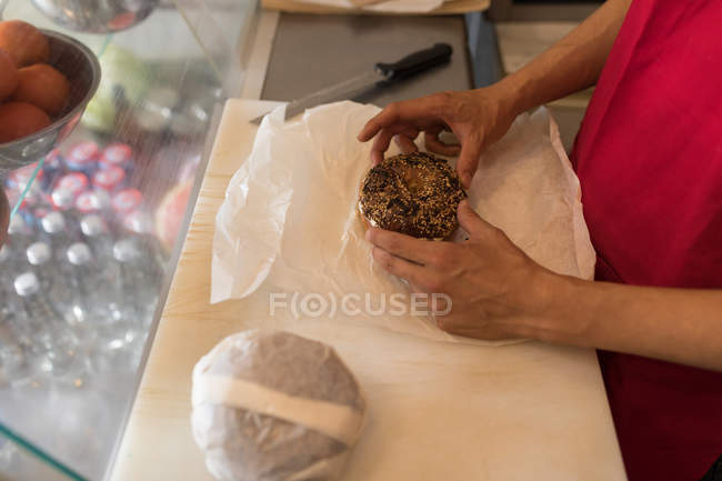Man wrapping a doughnut in the coffee shop — Stock Photo