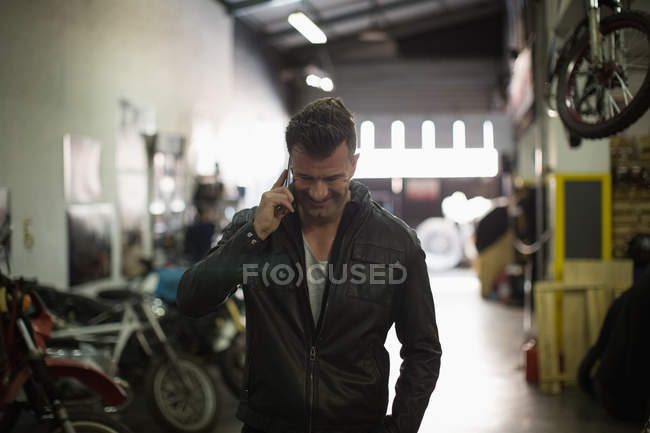 Mecánico hablando en el teléfono móvil en el garaje - foto de stock