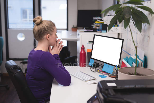 Ejecutiva femenina trabajando en la computadora en el escritorio en la oficina - foto de stock