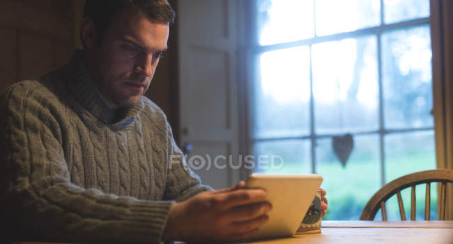 Внимательный человек с помощью цифрового планшета дома — стоковое фото