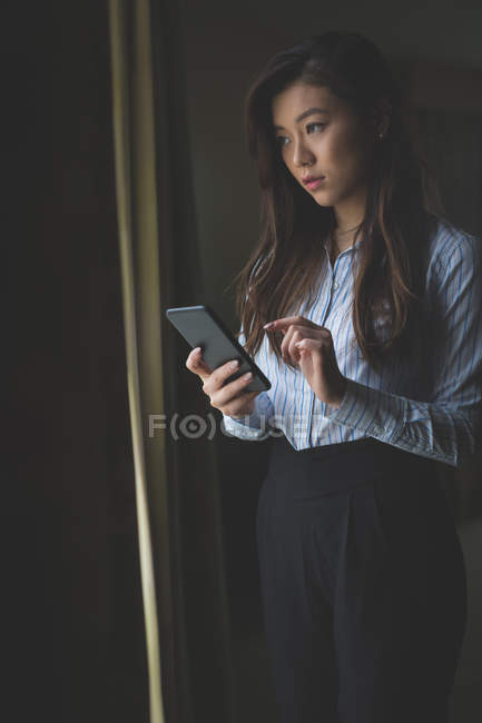 Donna d'affari che utilizza il telefono cellulare in camera d'albergo — Foto stock