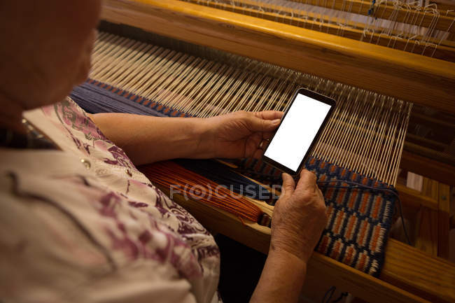 Крупним планом літня жінка використовує мобільний телефон в магазині — стокове фото
