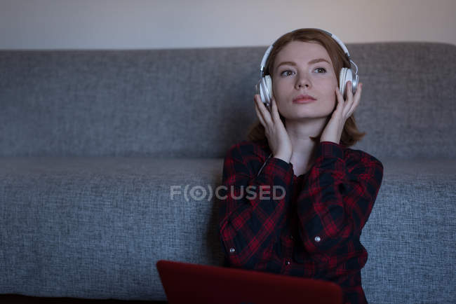 Молода жінка слухає музику у вітальні вдома — стокове фото