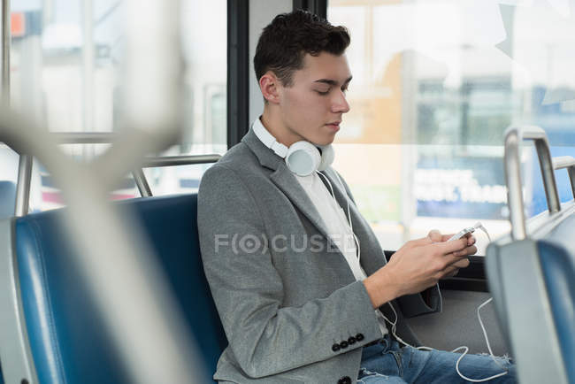 Vista lateral del hombre utilizando el teléfono móvil en autobús - foto de stock