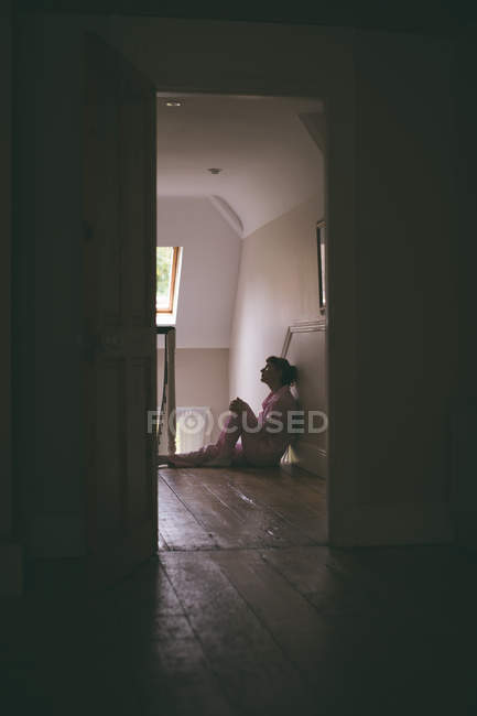 Donna premurosa seduta sul pavimento in legno a casa — Foto stock