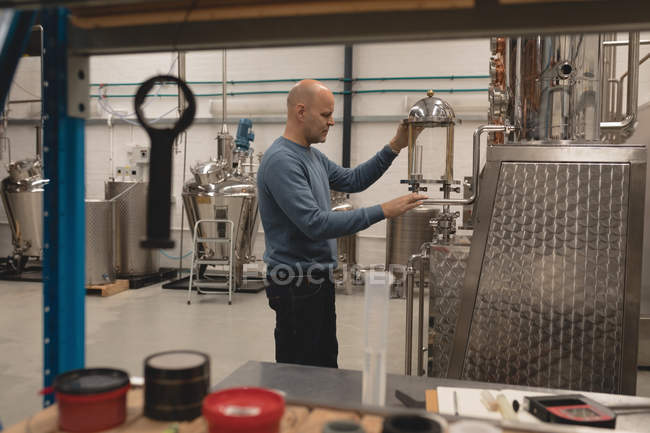 Чоловічий працівник перевіряє машину винокурні на заводі — стокове фото