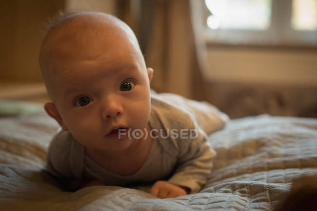 Портрет милого ребенка, лежащего на кровати в спальне — стоковое фото