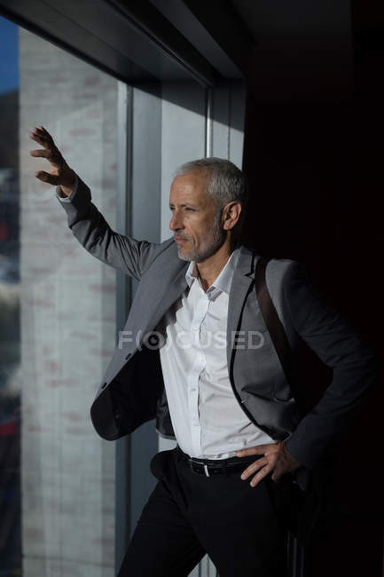 Бизнесмен смотрит в окно в гостиничном номере — стоковое фото
