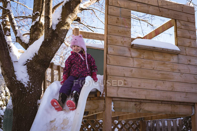 Menina bonito jogando no playground coberto de neve durante o inverno — Fotografia de Stock