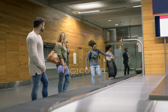 Commuters taking their baggage from baggage carousel at airport — Stock Photo