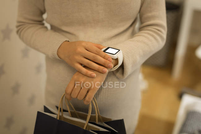 Donna incinta utilizzando smartwatch in negozio — Foto stock