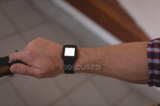 Close-up of man looking at smartwatch while cycling on sidewalk — Stock Photo
