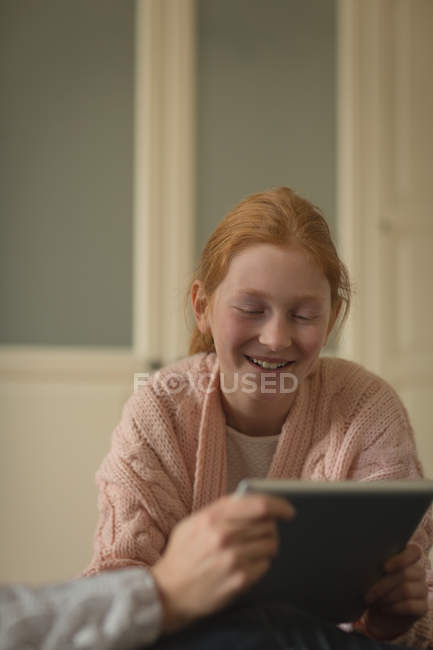 Madre e hija usando tableta digital en la sala de estar en casa - foto de stock