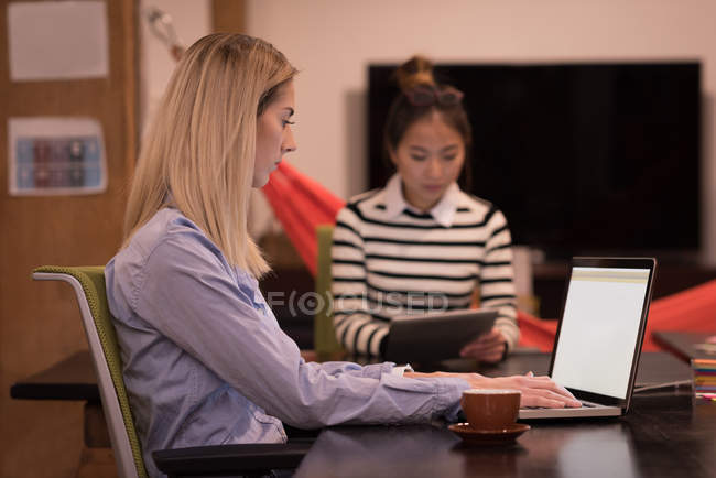 Жіночий керівників, використовуючи ноутбук та цифровий планшет на реєстрації в office. — стокове фото