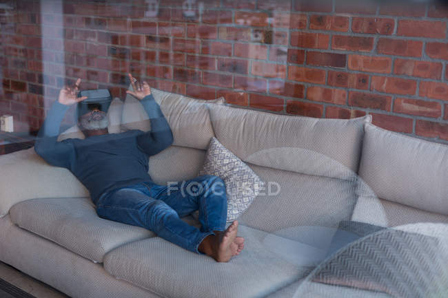 Старший мужчина использует гарнитуру виртуальной реальности дома — стоковое фото