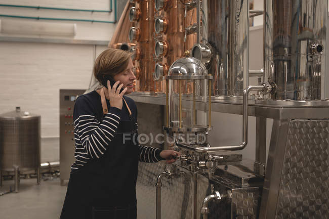 Trabalhadora do sexo feminino falando no telefone celular na fábrica — Fotografia de Stock