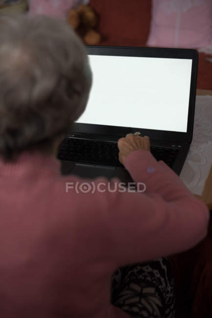 Vue arrière de la femme âgée utilisant un ordinateur portable à la maison — Photo de stock