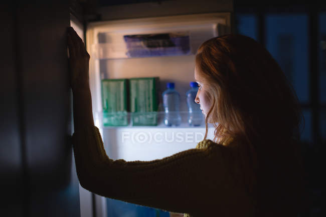 Femme ouvrant un réfrigérateur à la maison — Photo de stock
